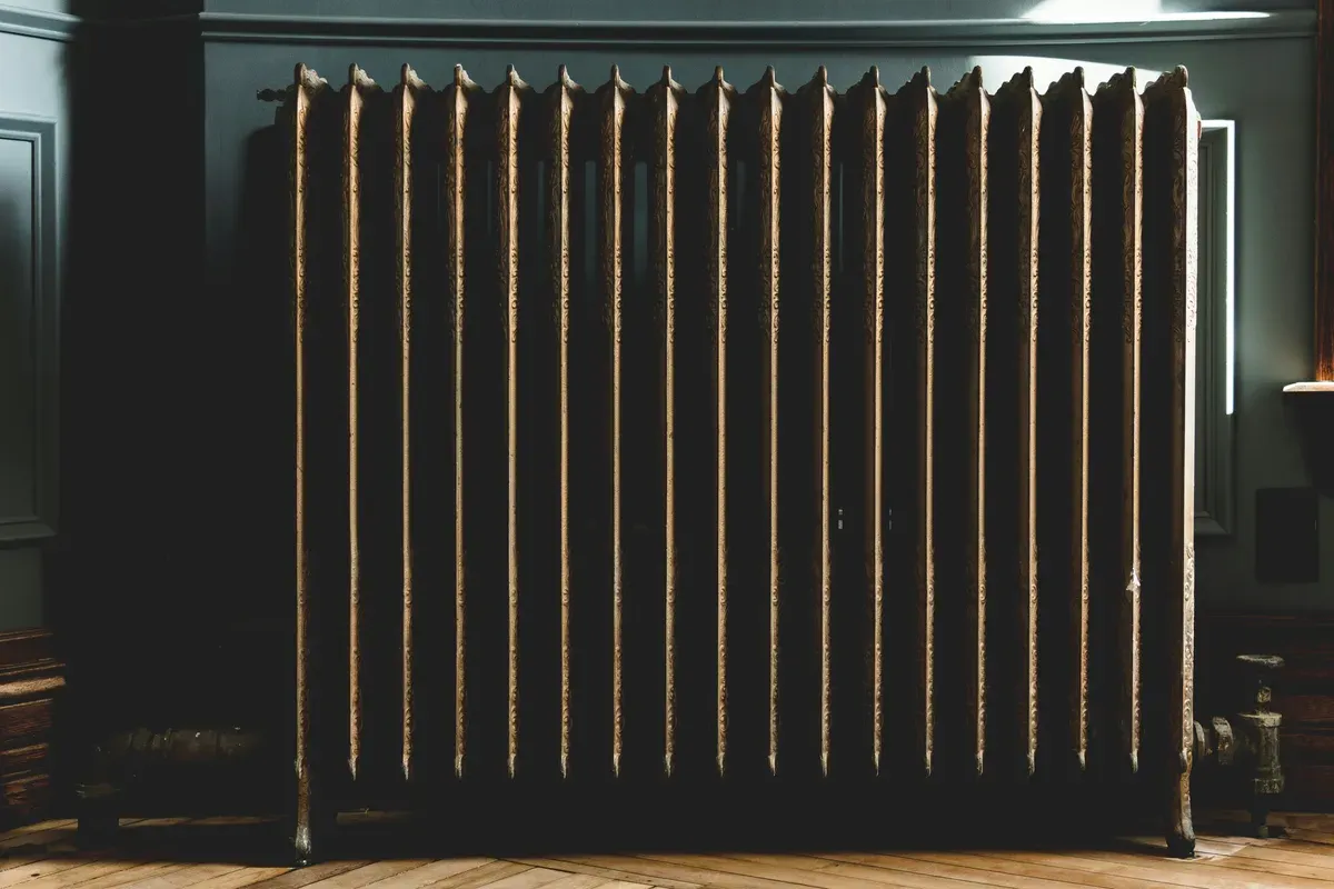 A grey oil filled heater standing on a floor