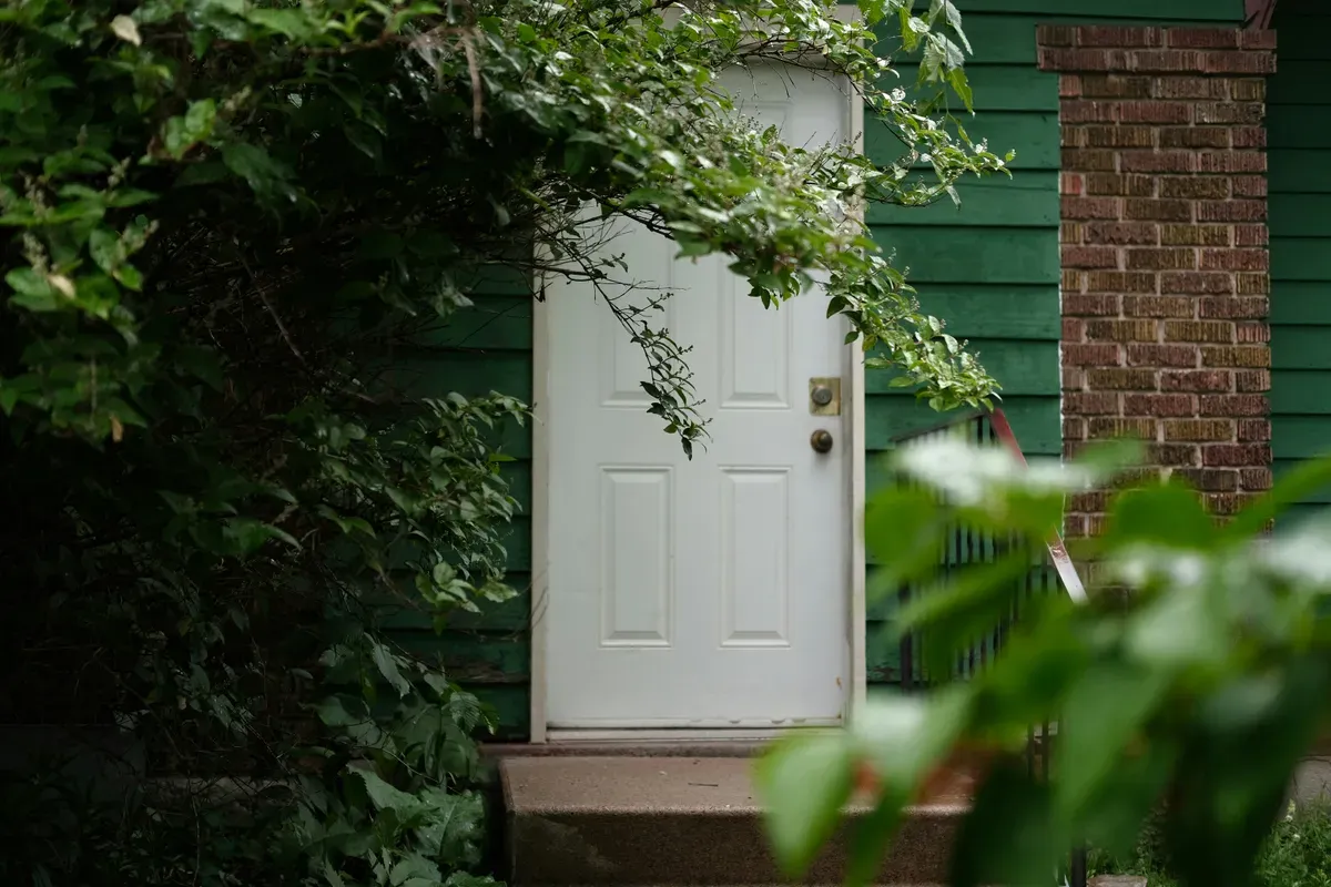 A front door half hidden by foliage, the thing an automation has to get right
