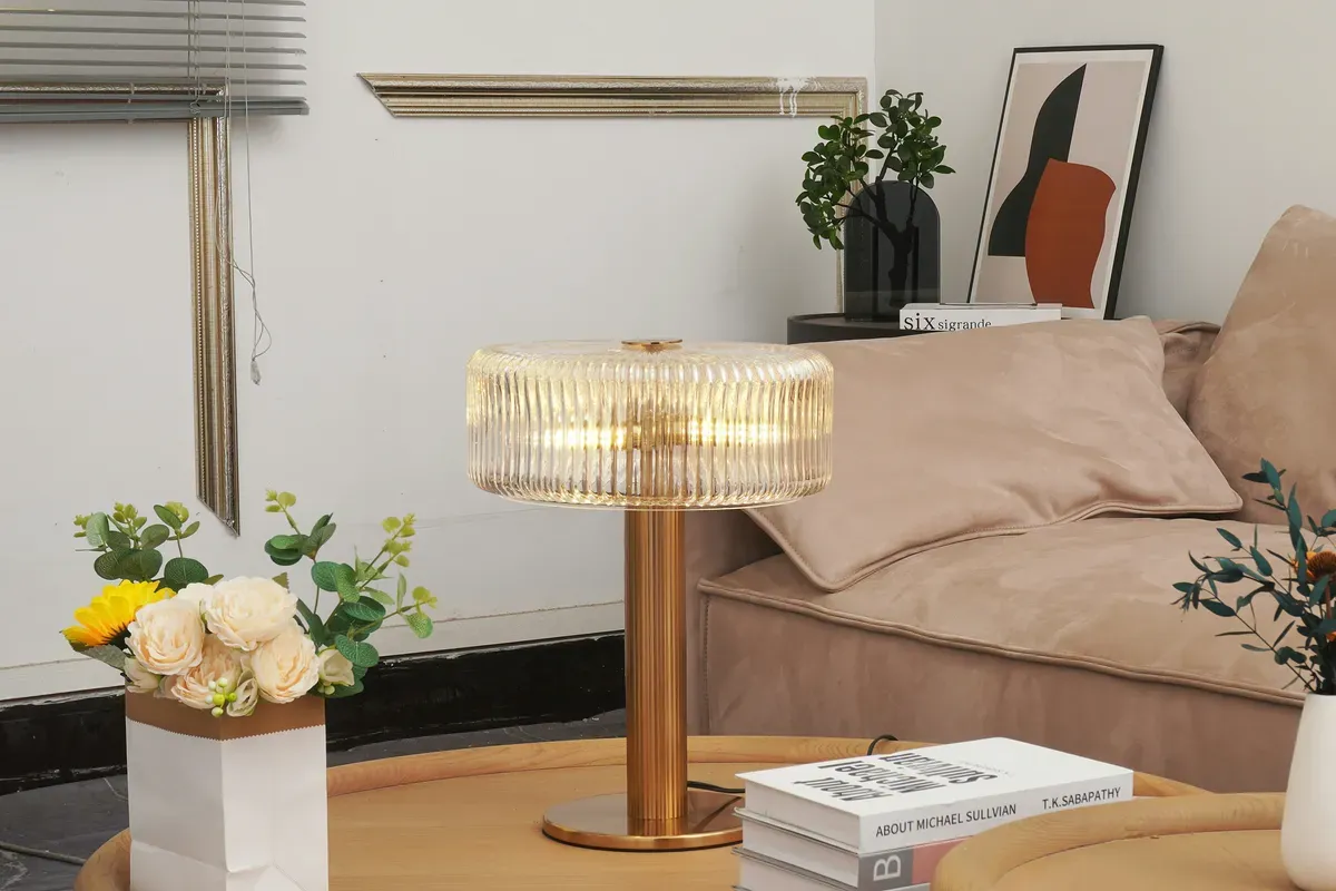 A table lamp glowing softly on a coffee table beside flowers