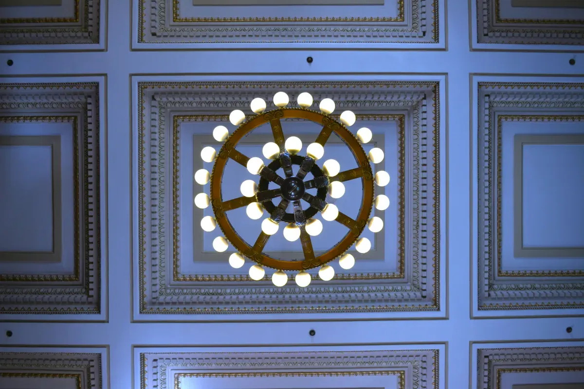 A grand circular chandelier lighting a coffered ceiling