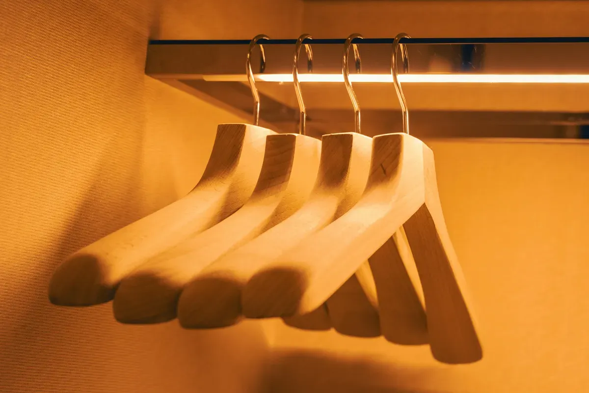 Wooden clothes hangers on a rail lit by warm light