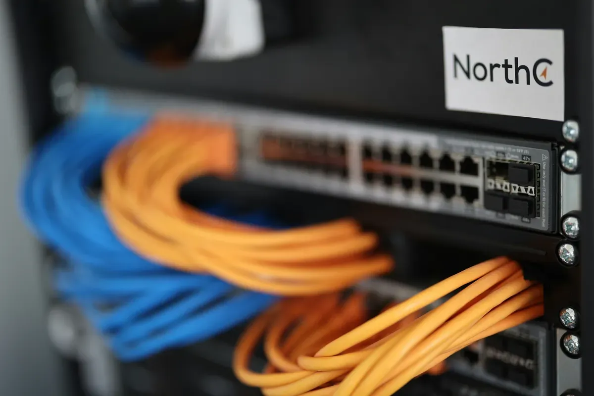 A patch panel and network switch inside a wall cabinet