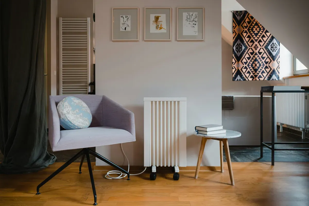 An electric heater standing in a room beside a chair