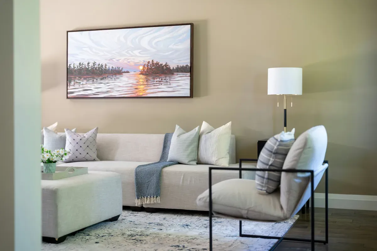 A living room with a light sofa, an armchair and a lamp