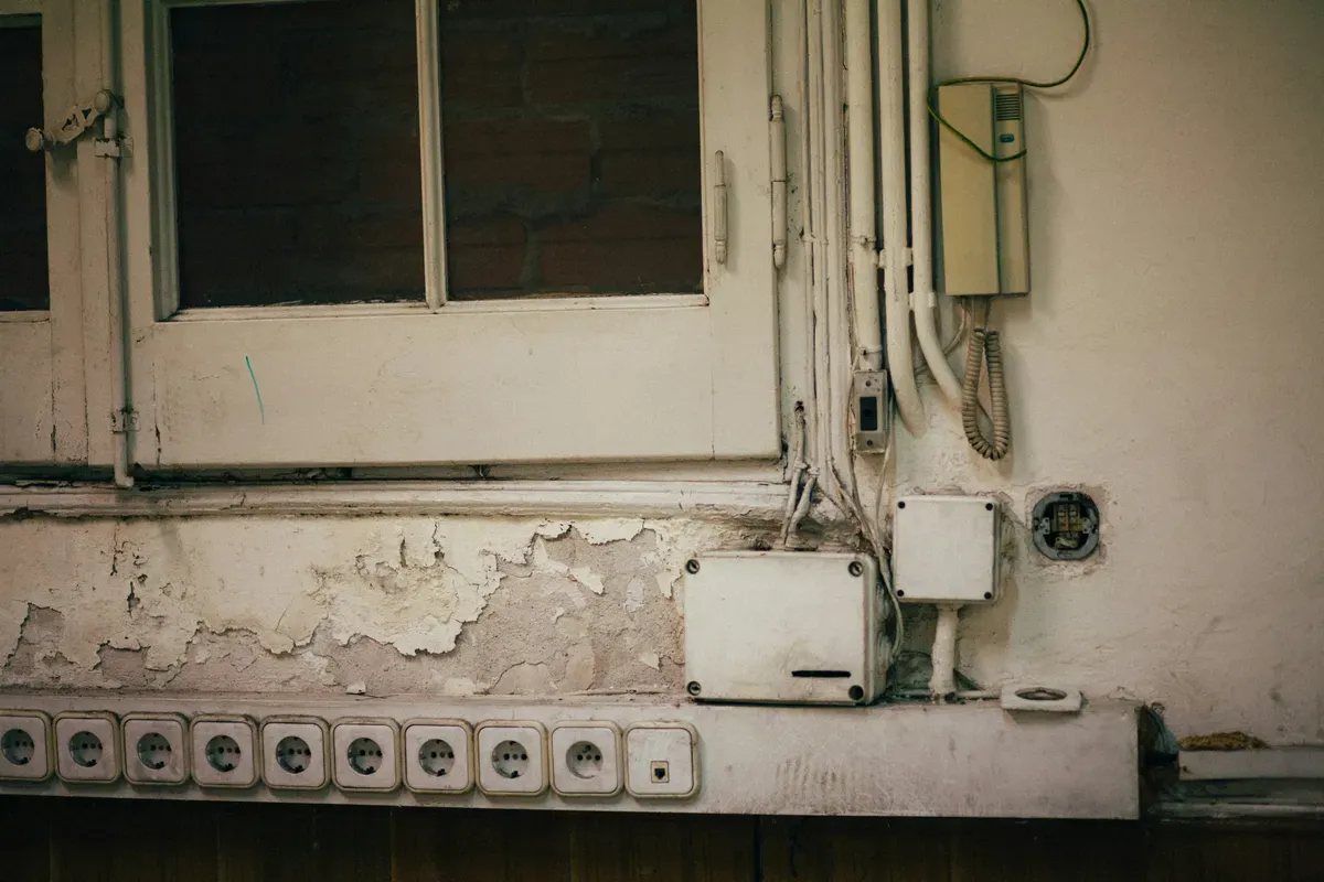 A wall with a bunch of wires hanging out of it