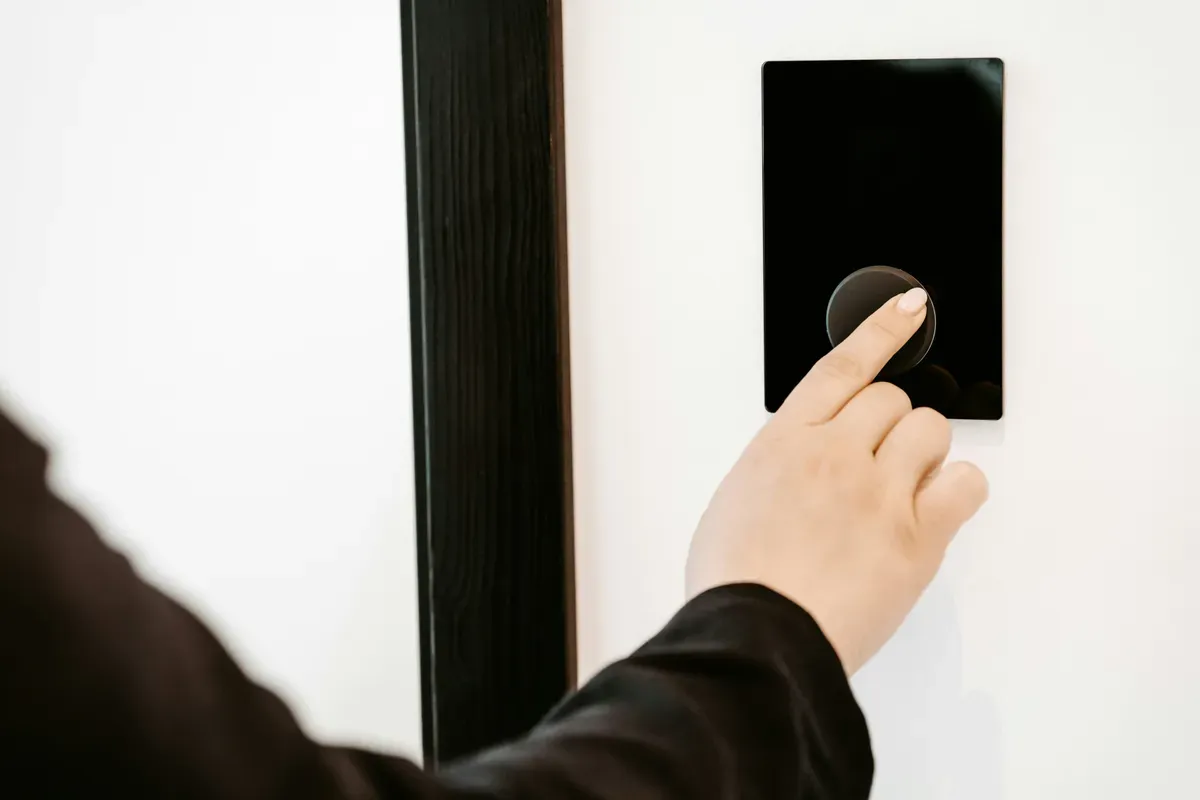 A finger pressing a button on a flat wall panel during first setup