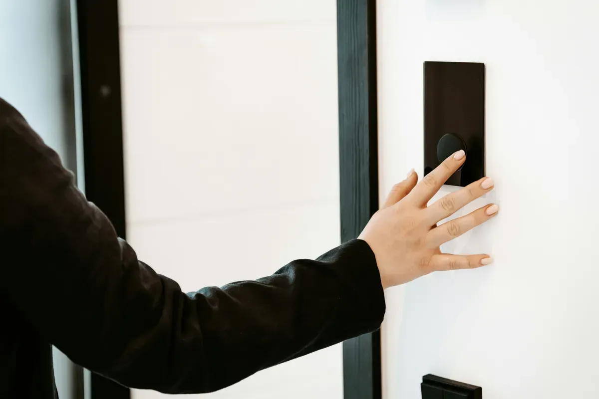 A finger touching a lit glass wall panel that replaced a mechanical switch