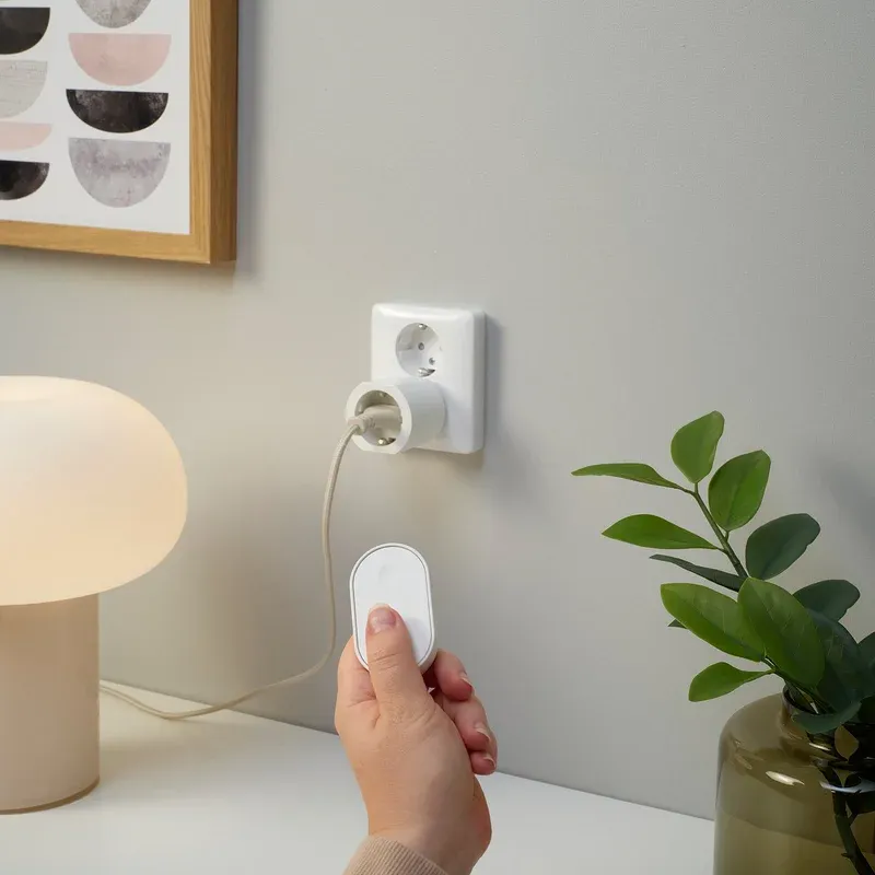 IKEA GRILLPLATS smart plug installed in a standard wall outlet next to furniture