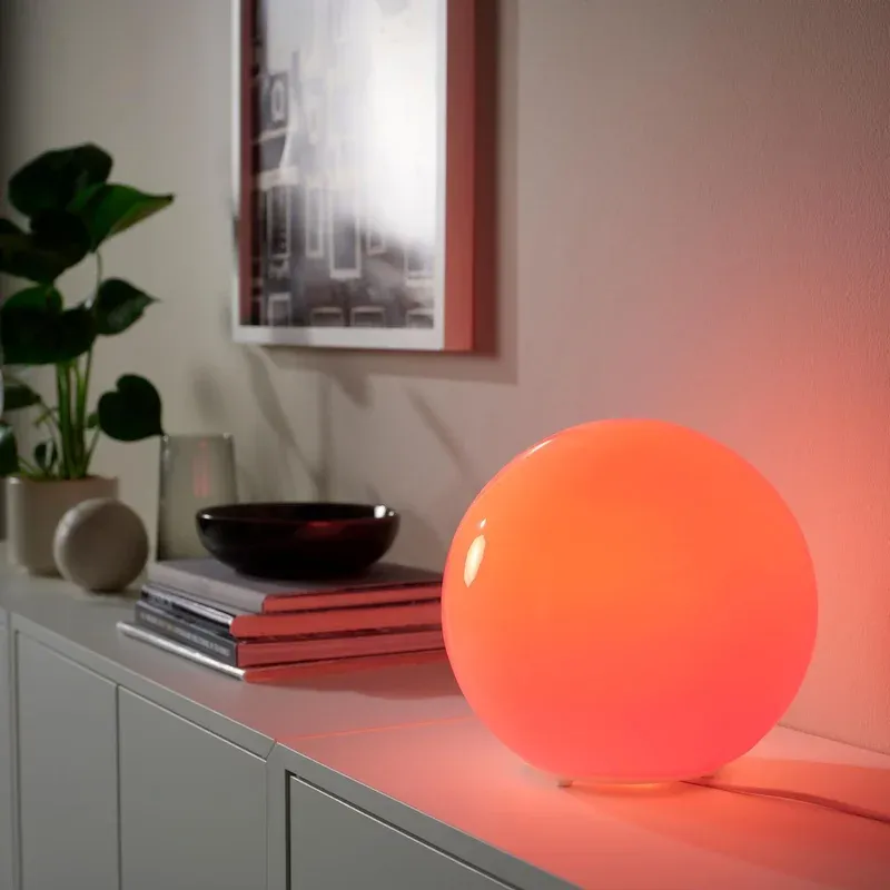 IKEA KAJPLATS smart bulb in a round red table lamp lifestyle shot