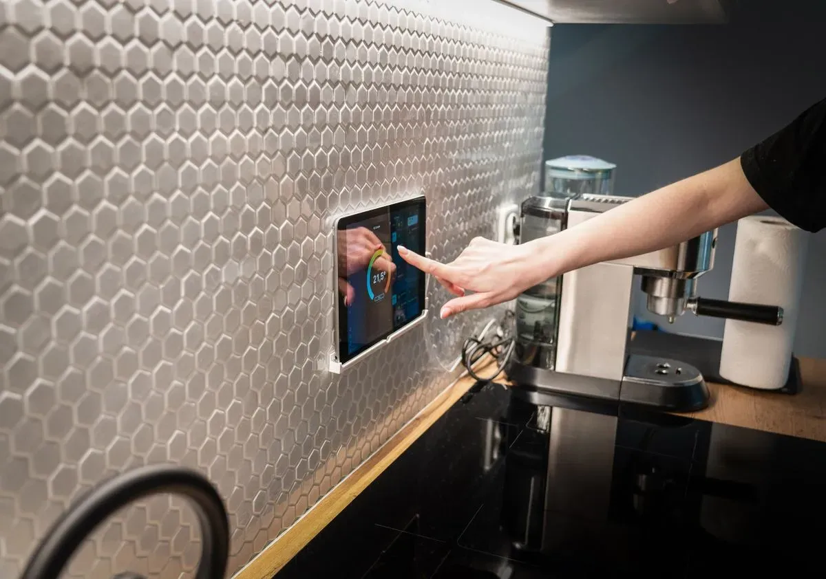 Touchscreen smart home control panel built into a modern kitchen wall