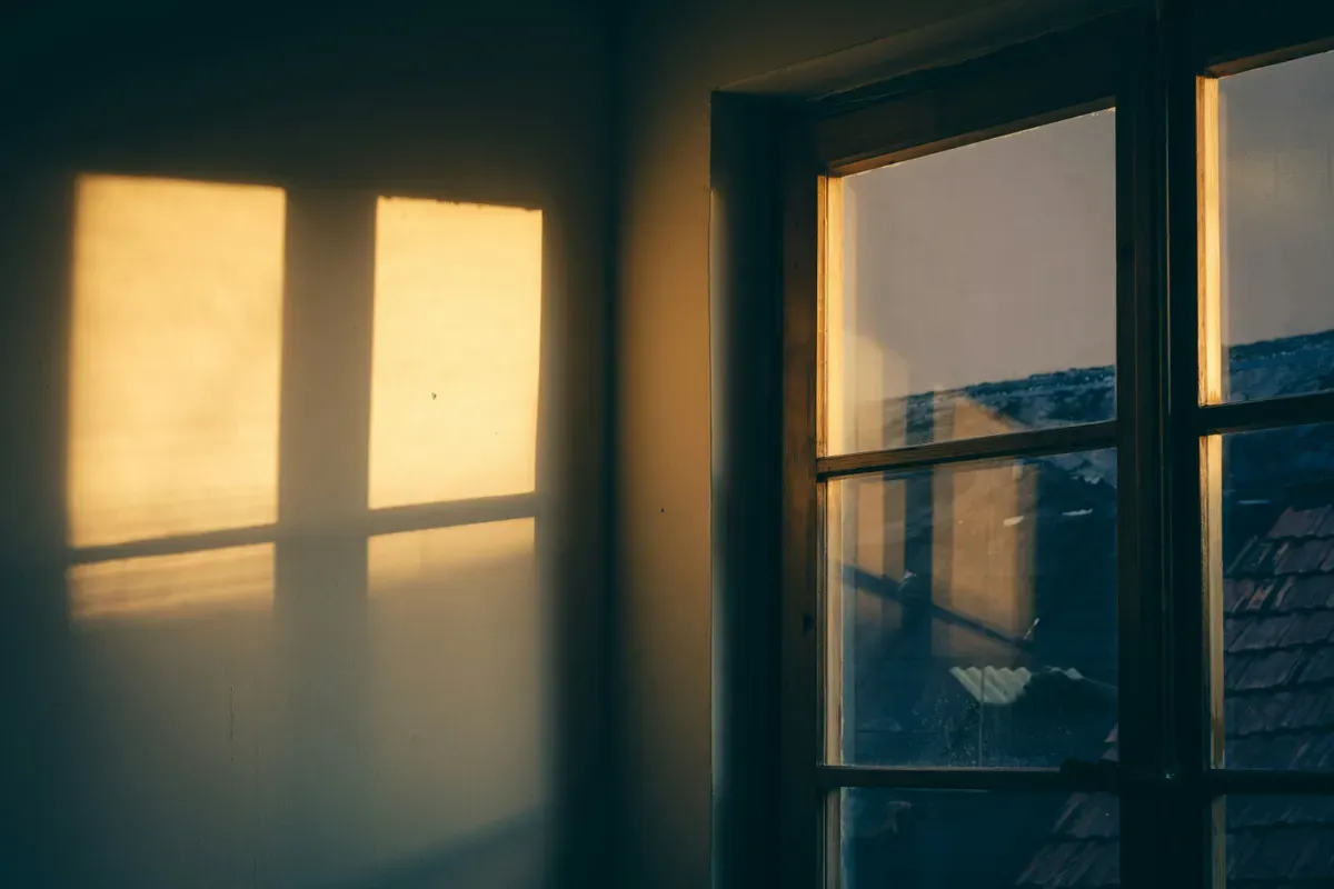 Low evening sun casting warm window-shaped light onto an interior wall beside a window