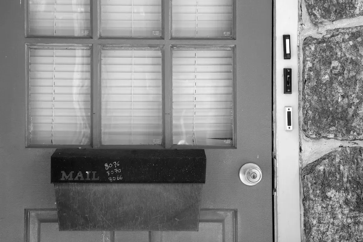 A row of doorbells beside a glazed entrance door