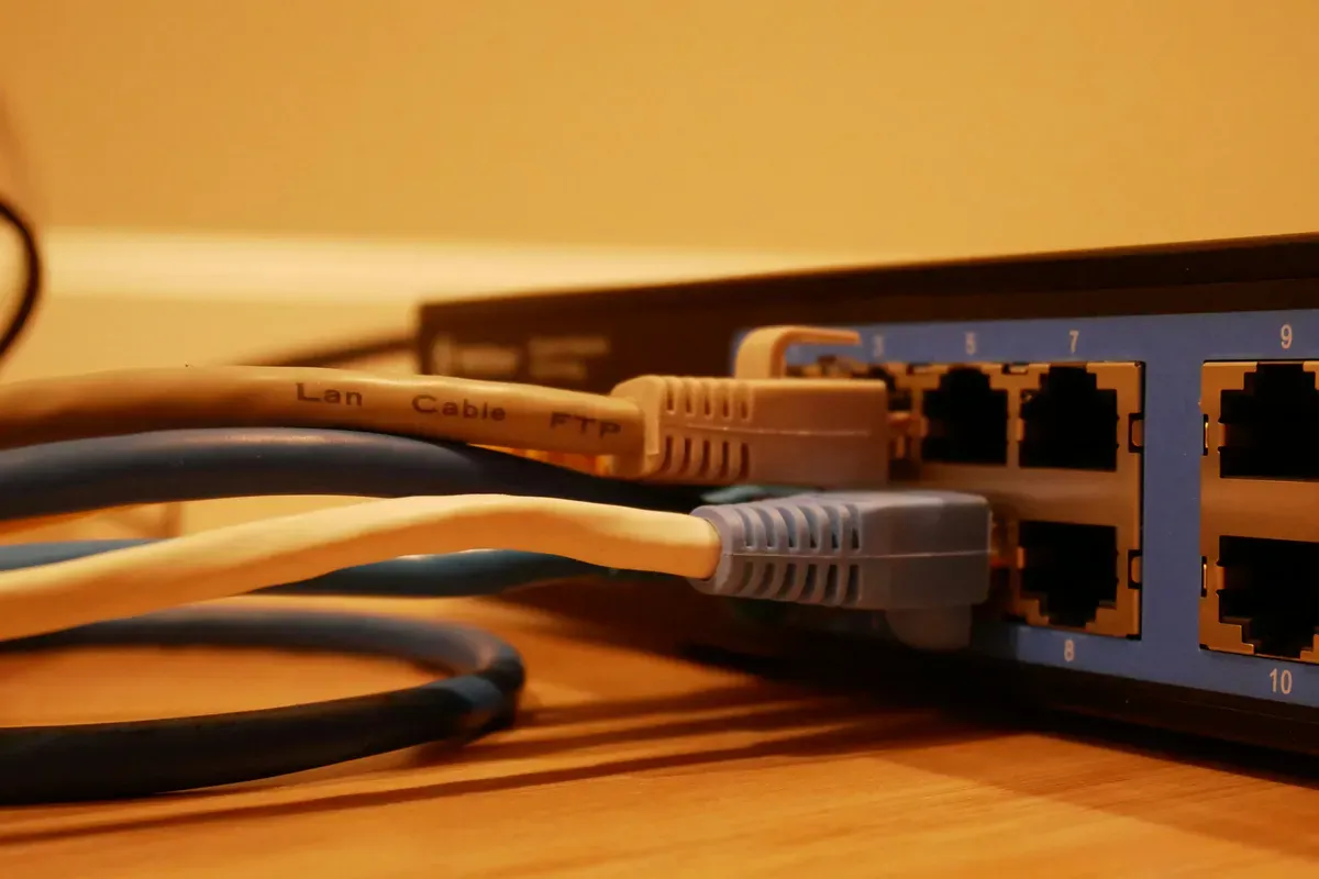 A grey network cable plugged into a switch port, with other cables in the foreground