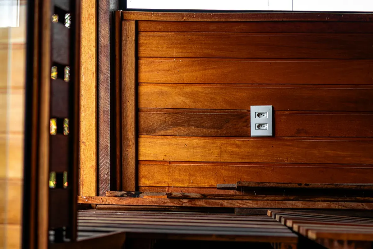 A white electrical outlet set into a warm wooden wall