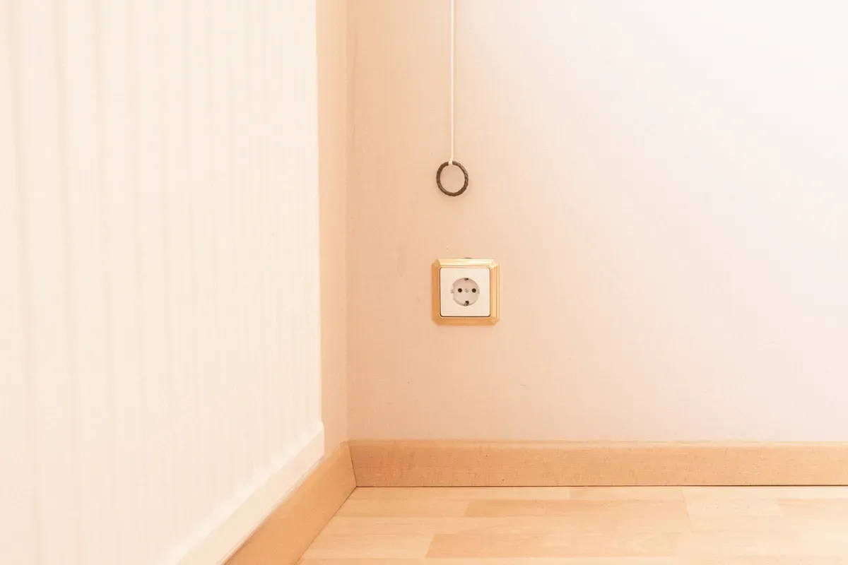A square white wall socket photographed straight on