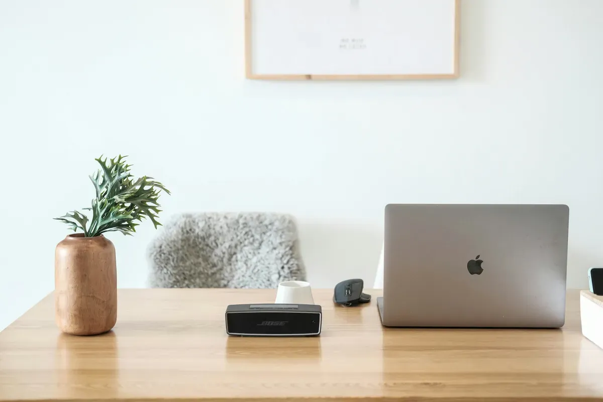 A laptop open on a wooden desk, the layout a wall panel has to beat