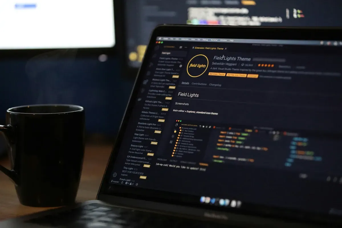 A laptop showing code beside a steaming mug