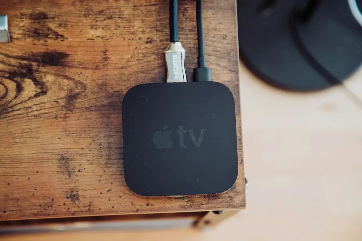 Black Apple TV box on a wooden table, one of the most common accidental Thread border routers