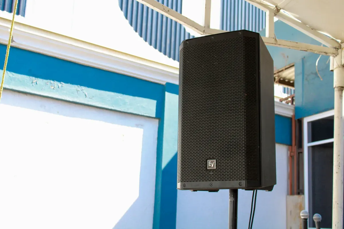 A black speaker mounted high on a pole