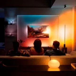 Group of people watching TV in a living room lit by warm Philips Hue dynamic scene via Bridge Pro