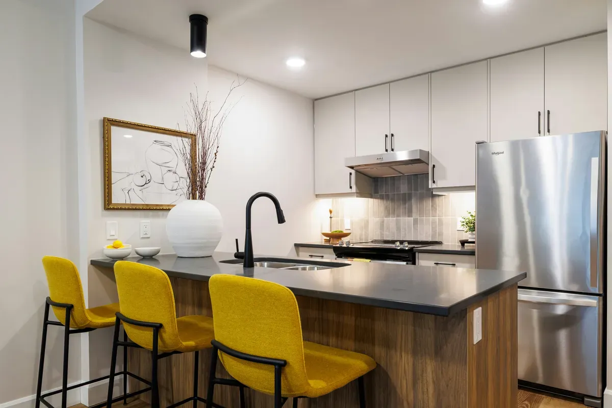 A kitchen island with yellow bar stools pulled up to it