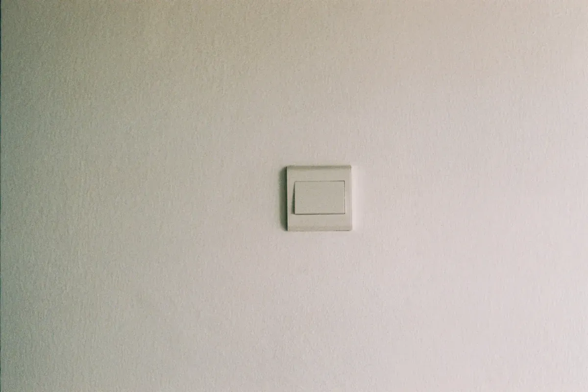 A plain white switch plate on a painted wall before any retrofit