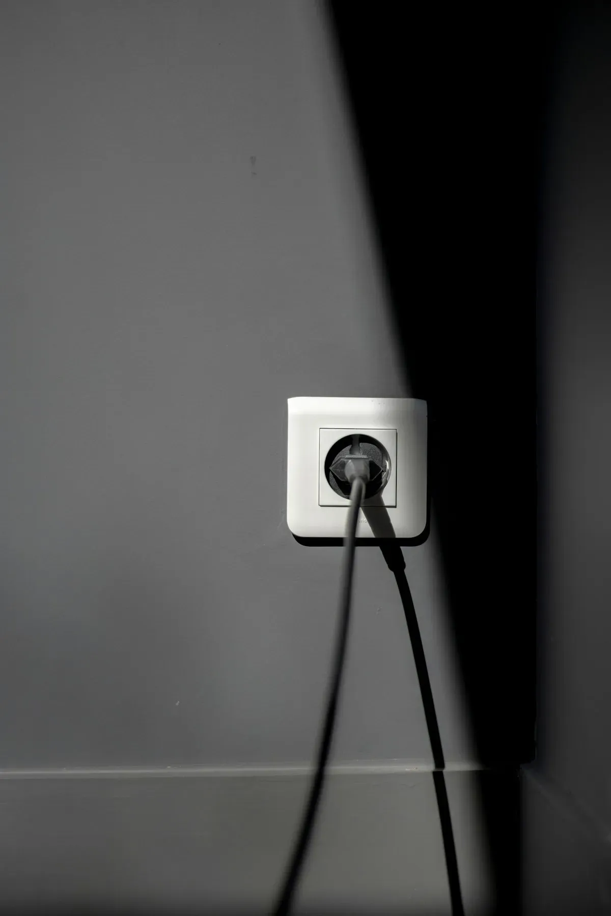 A plug inserted into a white power socket on a wall
