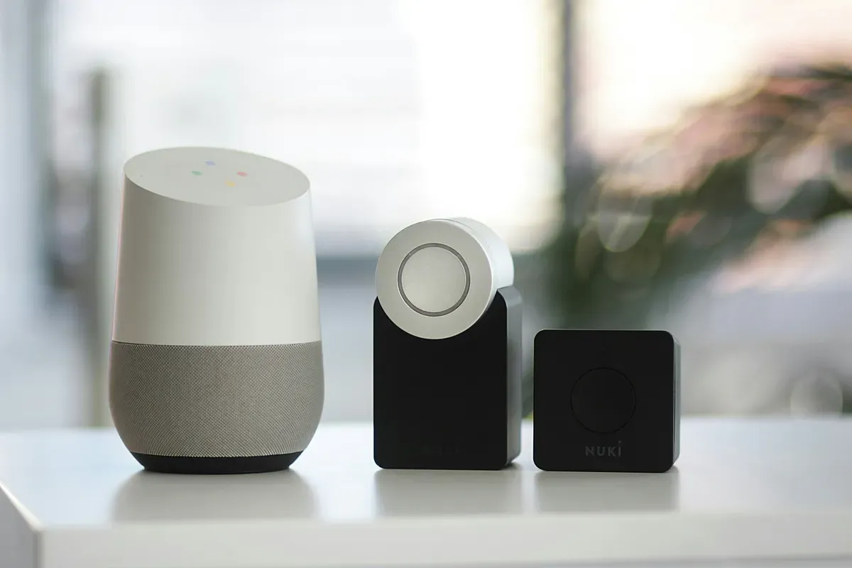 A white smart speaker beside two black speakers on a shelf