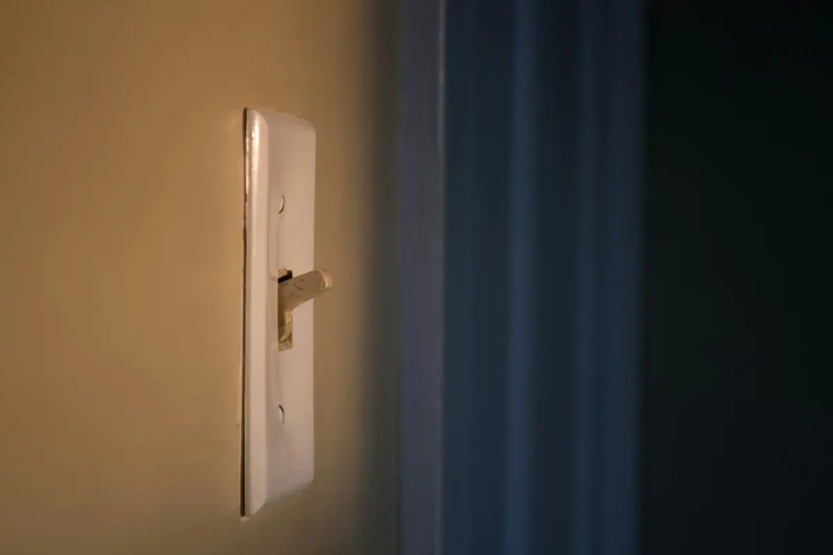 A white wall switch with a small toggle on a wall painted in warm tones
