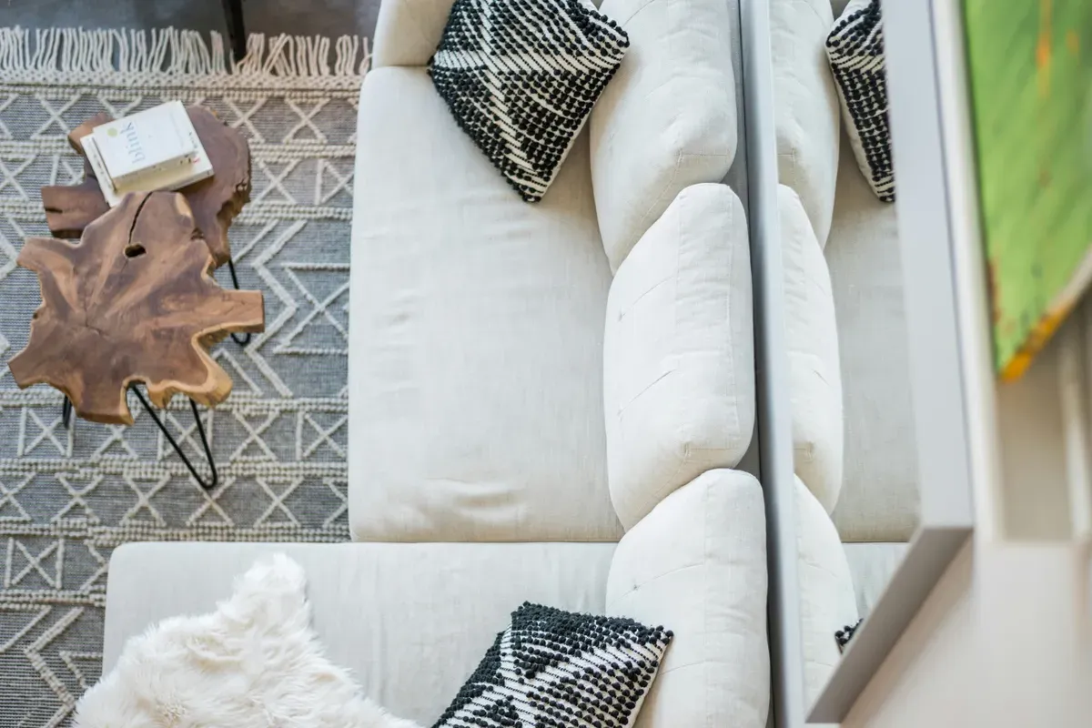 A white couch standing beside a mirror on the wall
