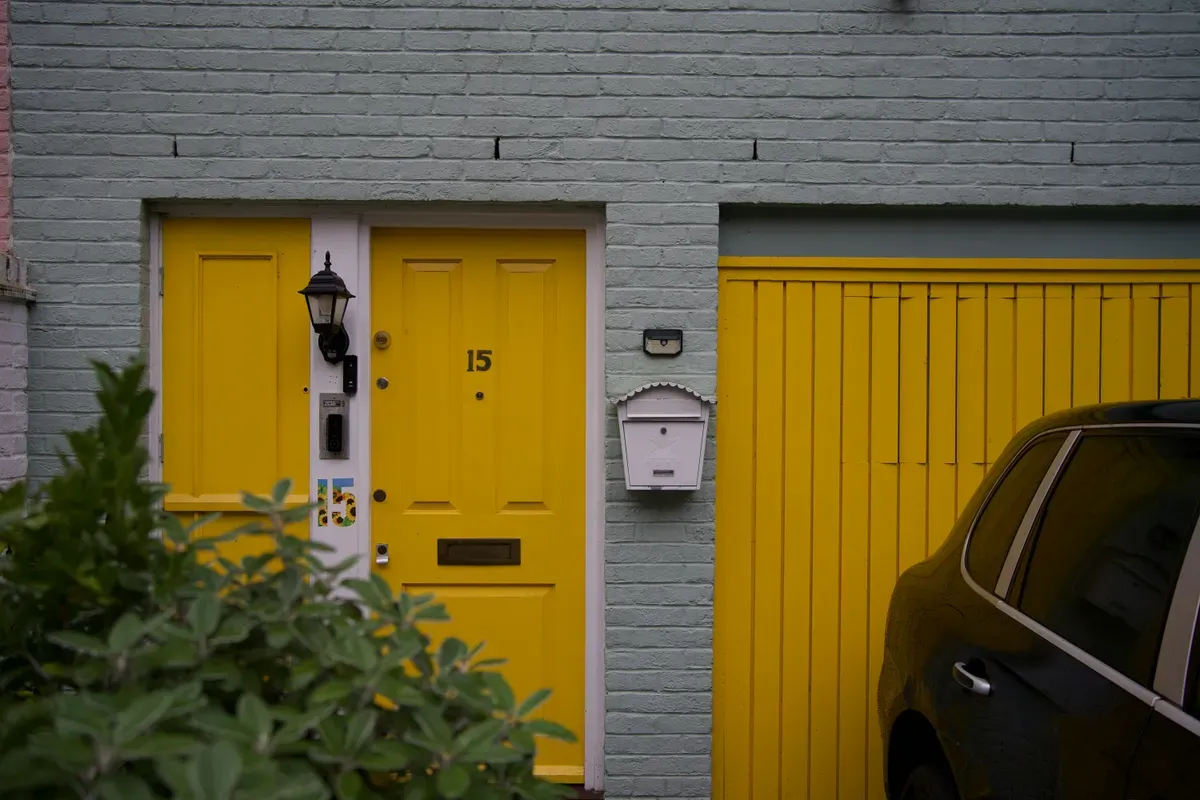 A garage beside a front door with a car parked outside