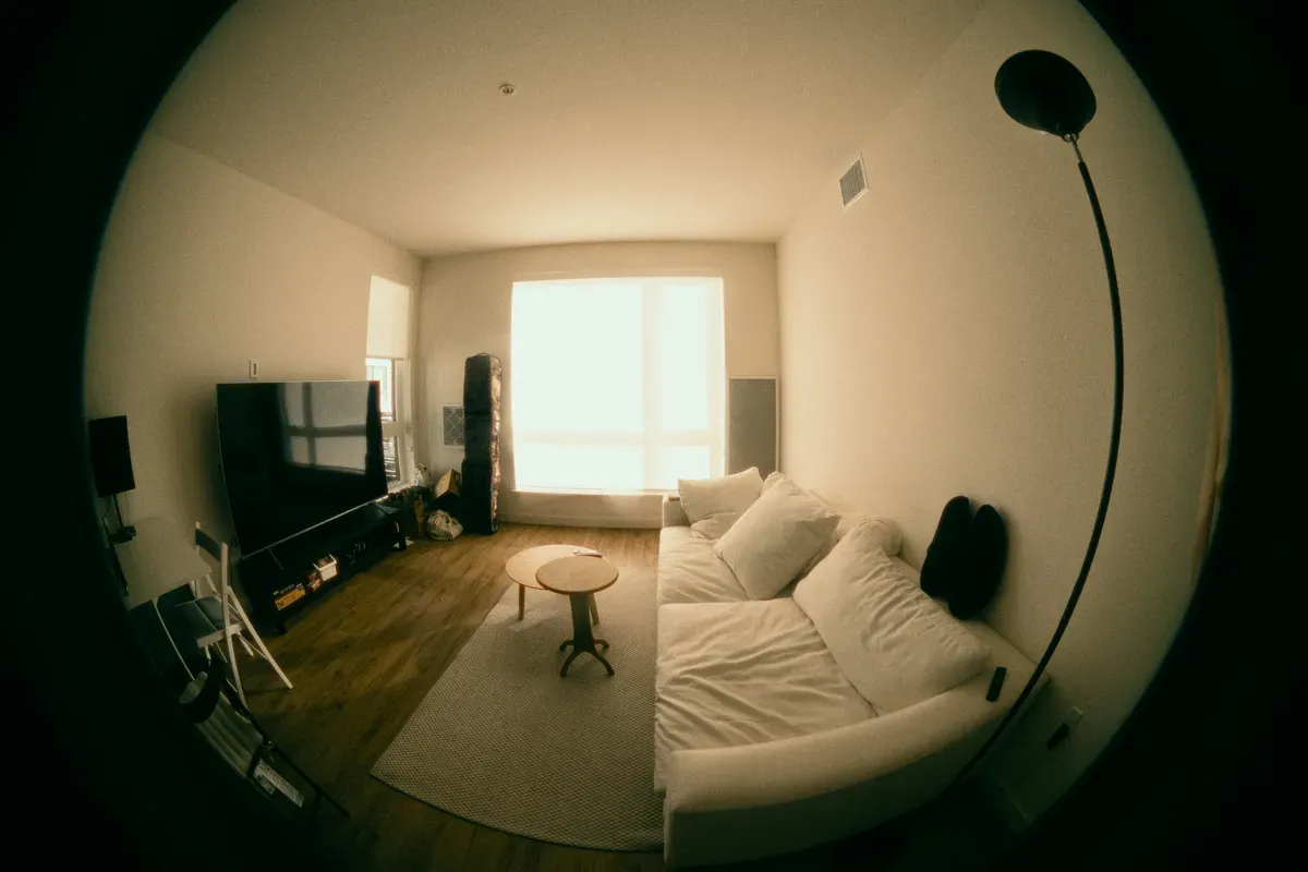 A quiet living room with a white sofa under a large window